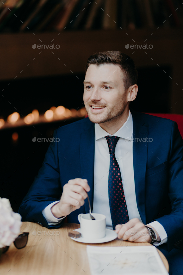 Handsome male in formal clothing, has cheerful expression, has dinner break at cafeteria