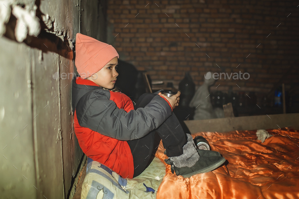 Ukrainian girl sits in bomb shelter, drinks tea and waits for end of airstrike of Russian invaders