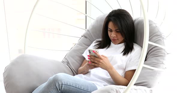 Black woman using phone while sitting on couch. alt