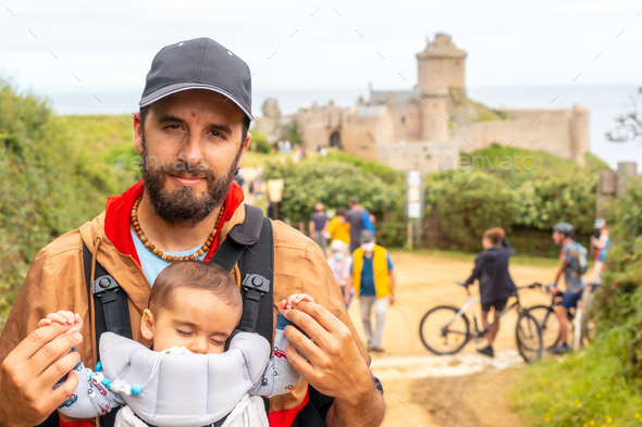 A young man with his son visiting the Fort-la-Latte castle by the sea at Cape Frehel