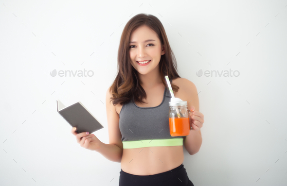 Asian woman drinking Fresh Raw Detox Vegetable Juice and reading a book in room.