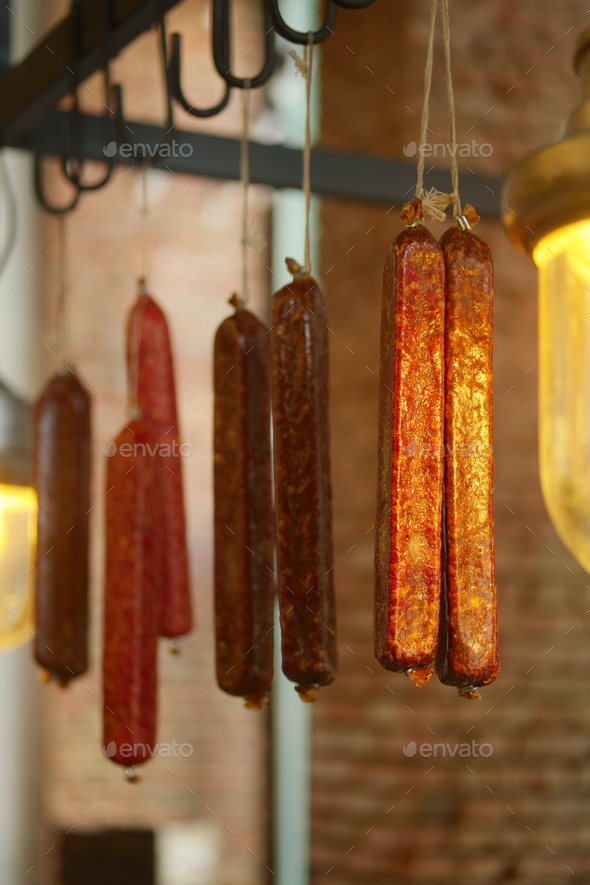 Smoked sausagees hanging on a hook under the ceiling