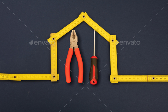 Home repair. Hand tools under house shape measure. Workshop, construction, renovation concept.