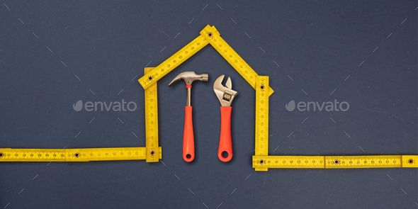 Home repair. Hand tools under house shape measure. Workshop, construction, renovation concept.