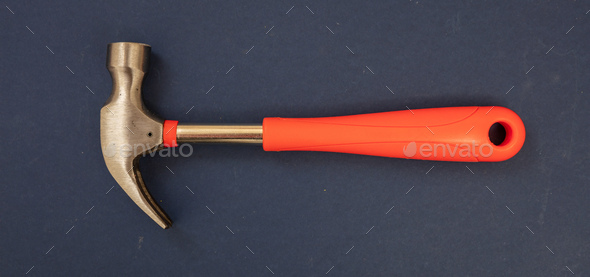 Hammer, steel head, orange color rubber handle on blue background. Overhead, close up view. Banner