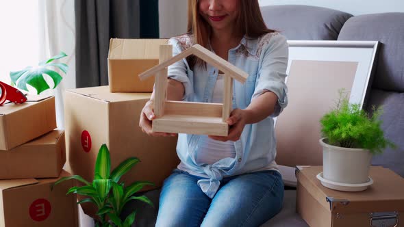 Happy young asian woman in living room at new house alt