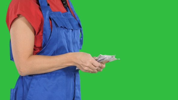 A woman in a workers clothes counts money on a Green Screen alt