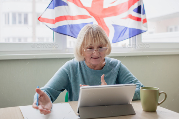 Senior woman learns English via internet with laptop, language classes for Ukrainian refugee