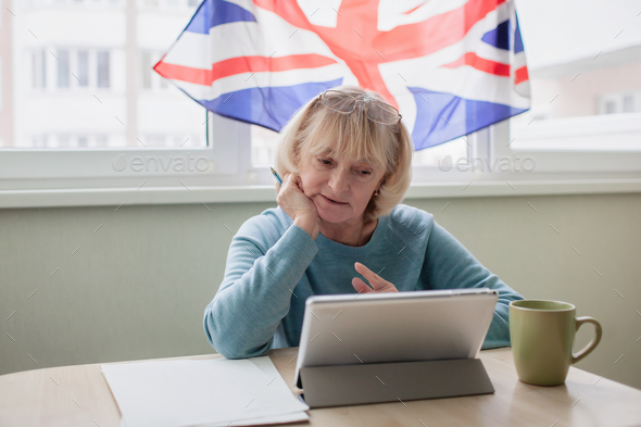 Senior woman learns English via internet with laptop, language classes for Ukrainian refugee