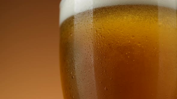 Pouring beer in glass. Cold Glass of beer close up with froth, rotation. alt
