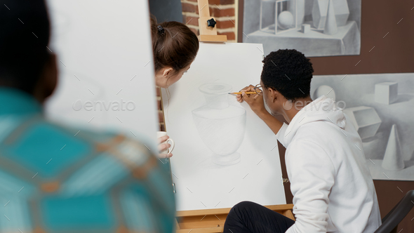 Young teacher talking to student about drawing design