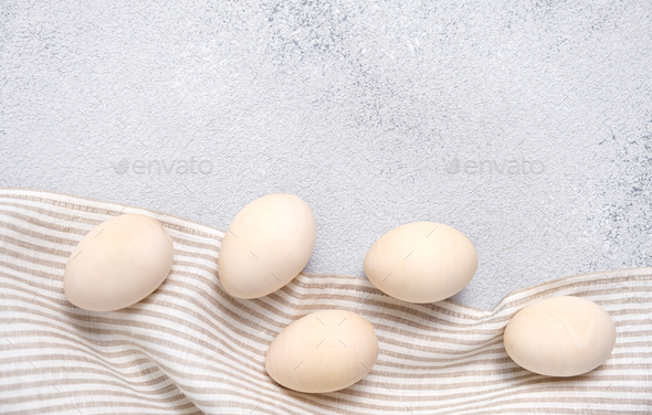 Five eggs on a striped linen napkin or towel on light gray textured background.