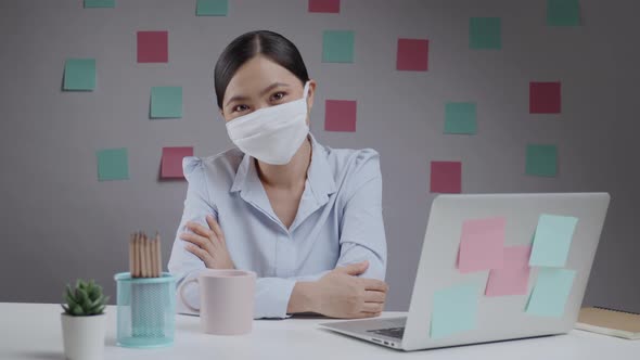 Asian woman wearing protective face mask working on a laptop