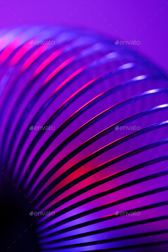 Closeup of coiled metal spring with sufficiently high strength and elastic properties in neon light