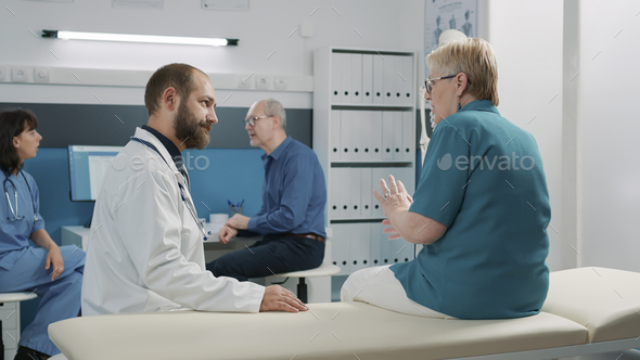 Male doctor consulting senior woman in medical cabinet