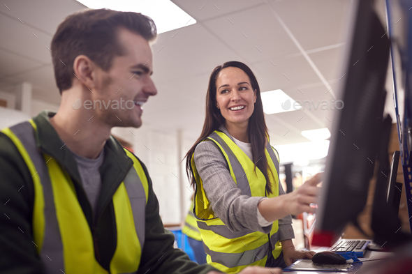 Staff In Busy Modern Warehouse Working On Computer Terminals