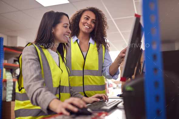 Female Staff In Busy Modern Warehouse Working On Computer Terminals