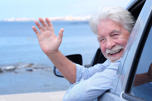 Smiling senior man sitting inside the car waving his hand looking at  camera, sea on background Stock Photo by lucigerma