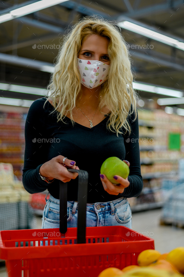 Woman in a supermarket jumping and wearing protective face mask while grocery shopping