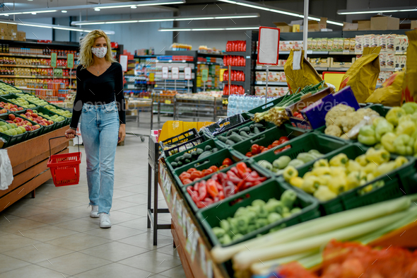 Woman in a supermarket jumping and wearing protective face mask while grocery shopping