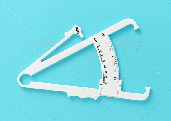 White caliper on blue background. Overhed. Slimming treatment concept.