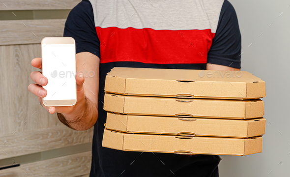 Man from delivery service holding pizza boxes and smartphone with mock up. Internet food order.