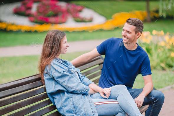 Relaxed young family on the bench in the park Stock Photo by ...