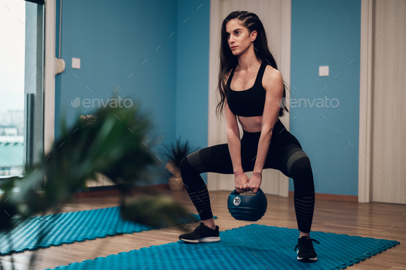 Woman practicing kettlebell squat with personal trainer at gym stock photo