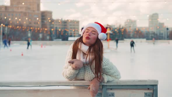 Young Smiling Woman Santa Hat Ice Skating Outside on Ice Rink Dressed White Sweater alt