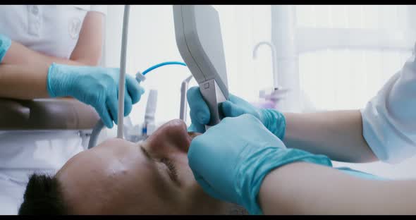 A Patient Lies in a Dental Chair While a Doctor Examines His Teeth Using Camera alt