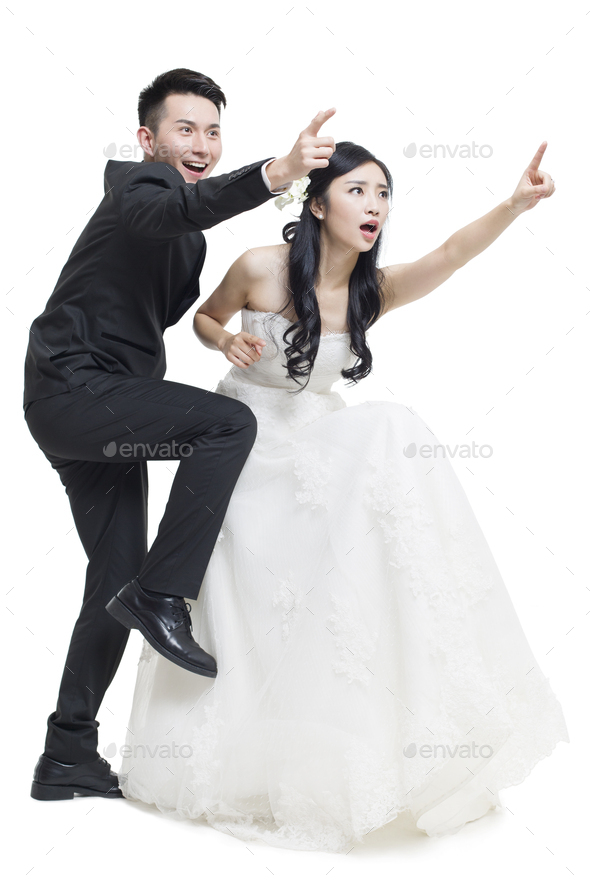 Humorous bride and groom pointing - Stock Photo - Images