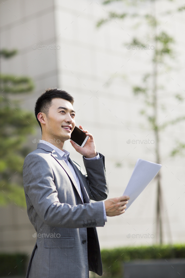 Young businessman on the phone with file in hand