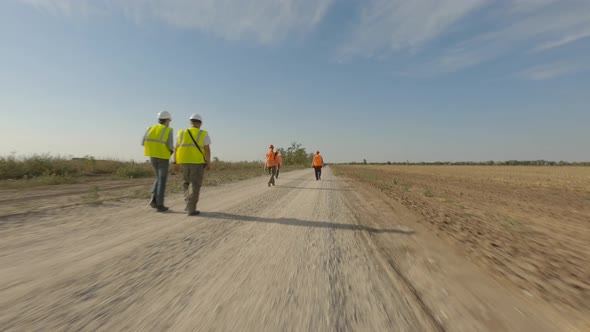 Builders Walking on Road Near Windmill in Field alt