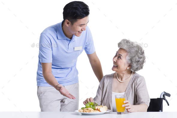 Nursing assistant serving food for disabled senior woman