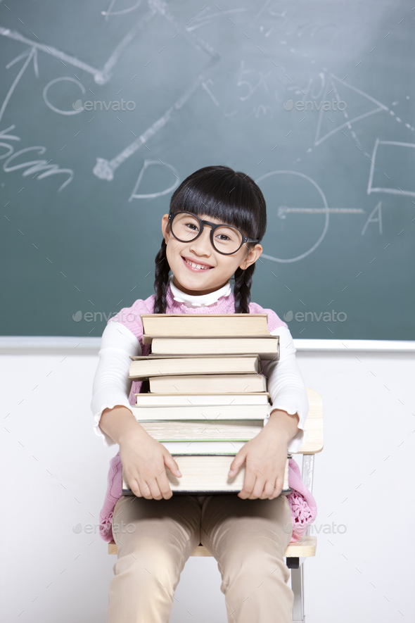 Humorous little girl with textbooks in classroom - Stock Photo - Images