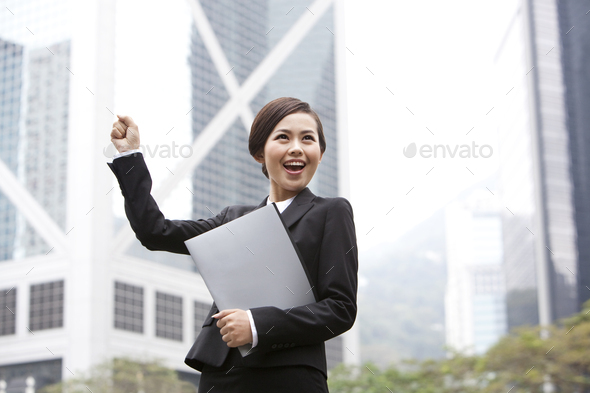 Happy businesswoman punching the air with portfolio in hand, Hong Kong