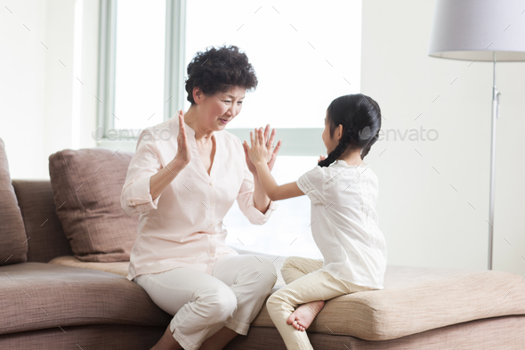 Happy grandmother and granddaughter playing clapping game