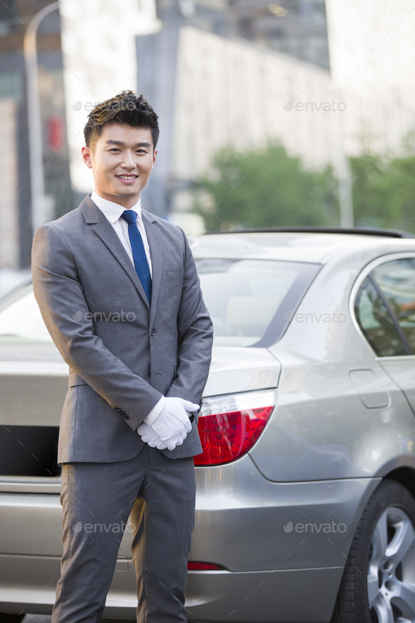 Portrait of chauffeur standing next to the car