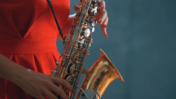 Beautiful Woman in Red Concert Dress Playing a Melody on Saxophone