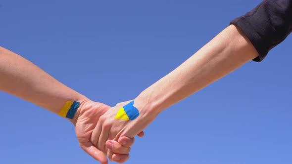 Kiev Ukraine 25 FEBRUARY 2022 Females Holding Hands Painted in Ukraine Flag Colors