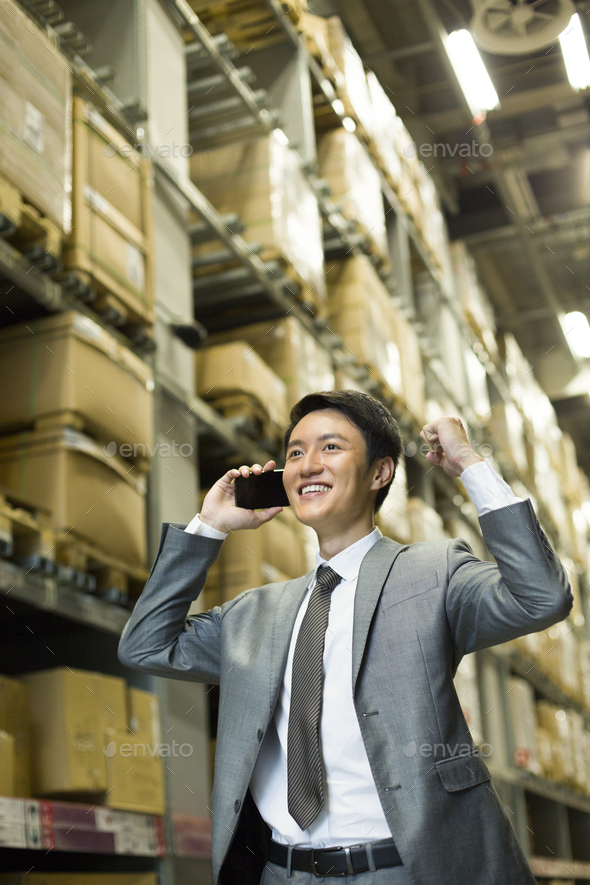 Businessman punching the air in warehouse