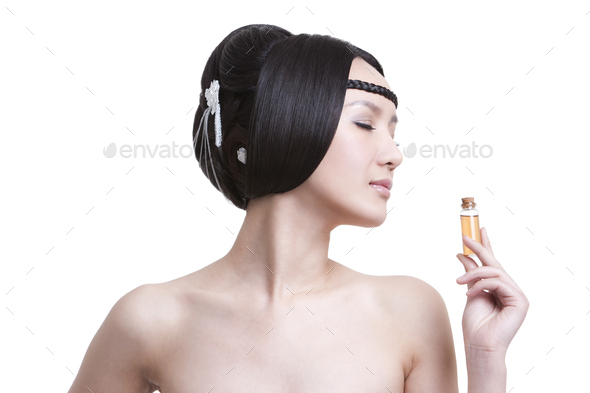 Young beautiful woman smelling a bottle of essential oil