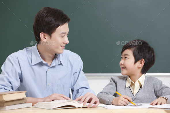 Happy schoolboy and teacher face to face in classroom
