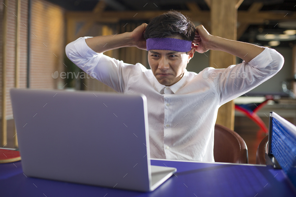 Young businessman using laptop on table tennis table - Stock Photo - Images