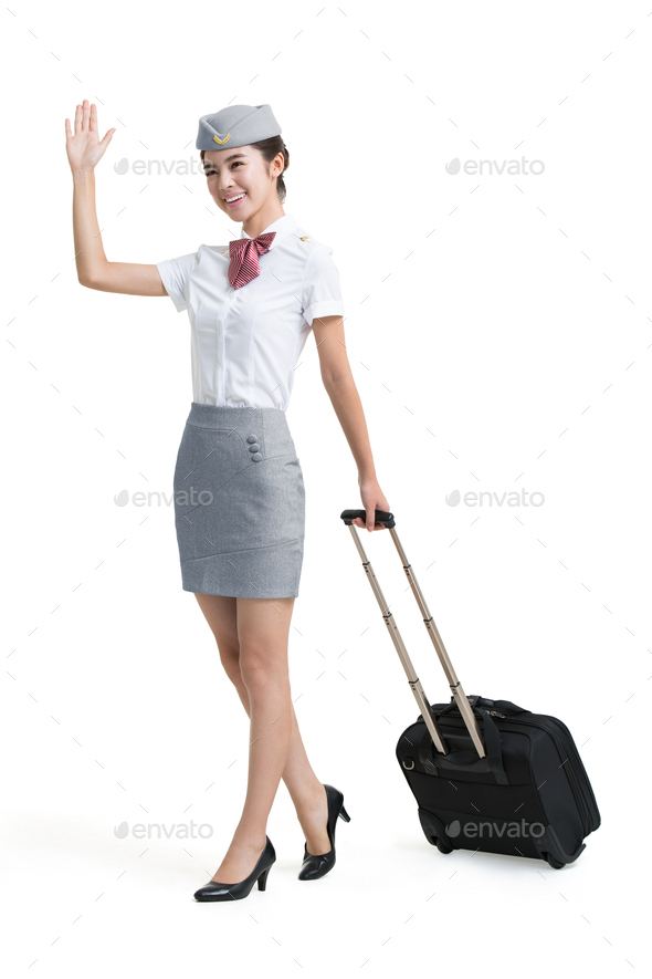 Smiling airline stewardess with wheeled luggage greeting