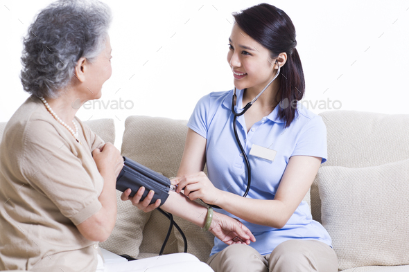 Nursing assistant taking senior woman\'s blood pressure
