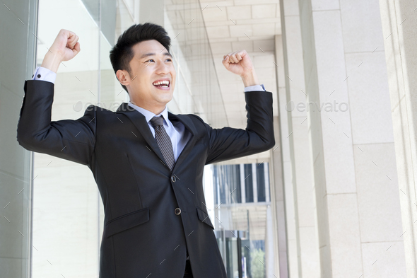 Cheerful businessman punching the air in CBD