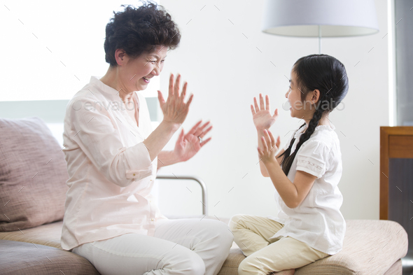 Happy grandmother and granddaughter playing clapping game