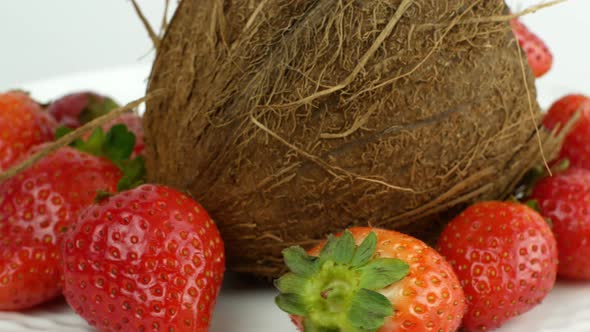 Tropical fruits coconut and strawberry rotates on a white background. Slow spinning exotic fruits