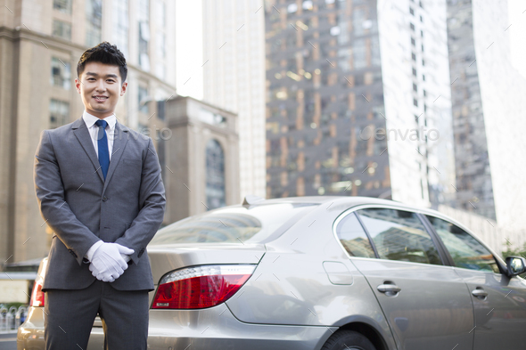 Portrait of chauffeur standing next to the car